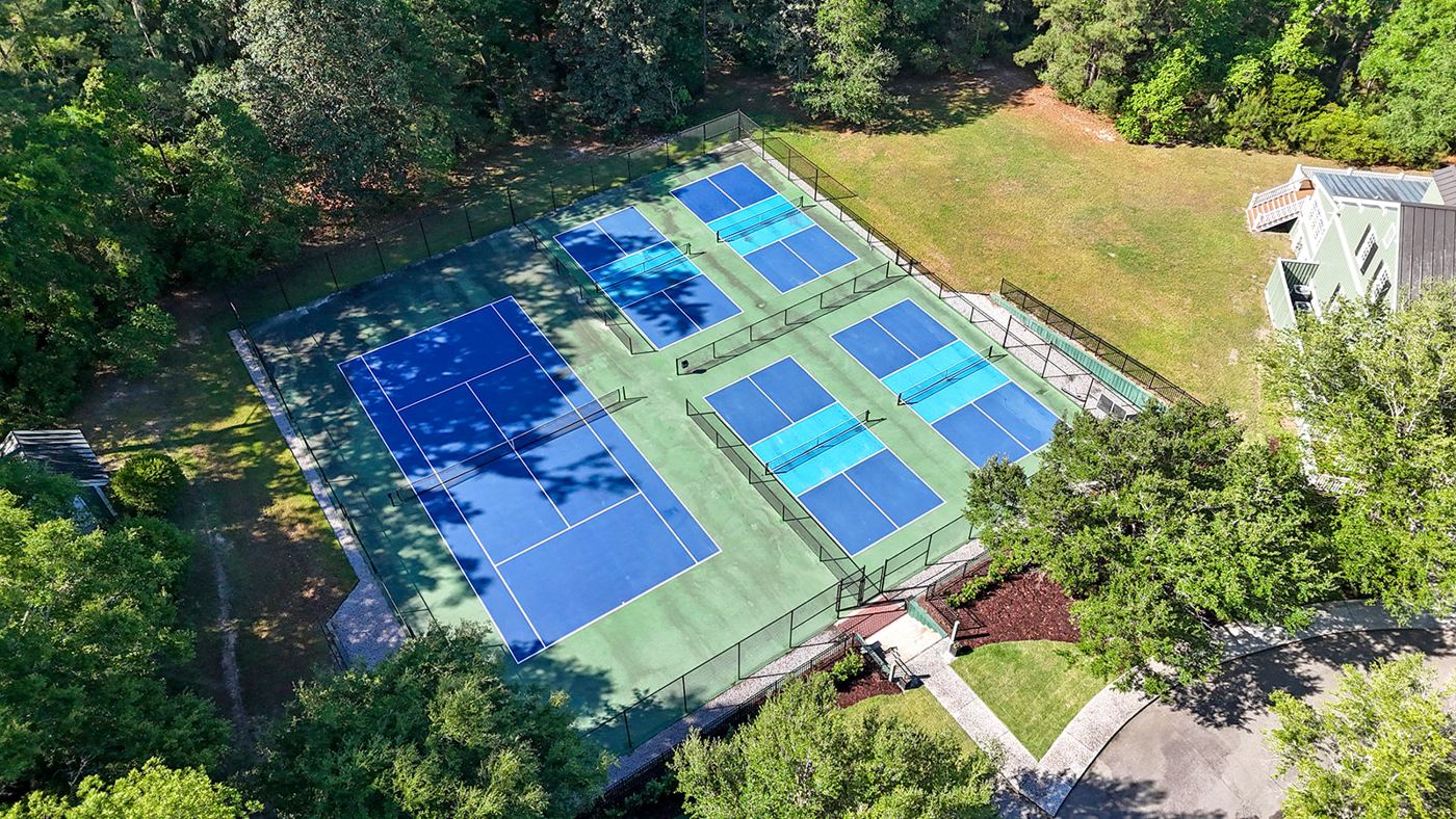 Tennis and pickleball courts surrounded by mature trees
